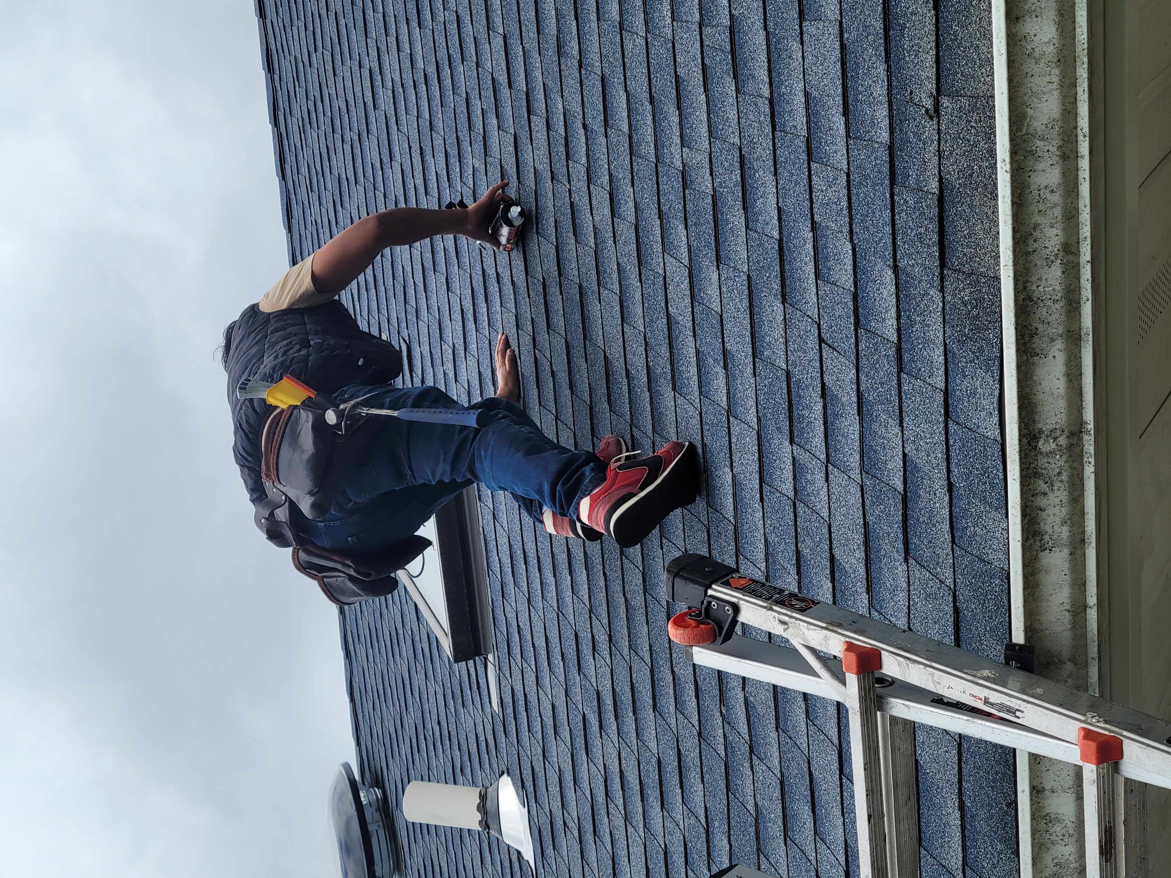 Jersey Strong crew member detailing roof flashing and sealant near a skylight